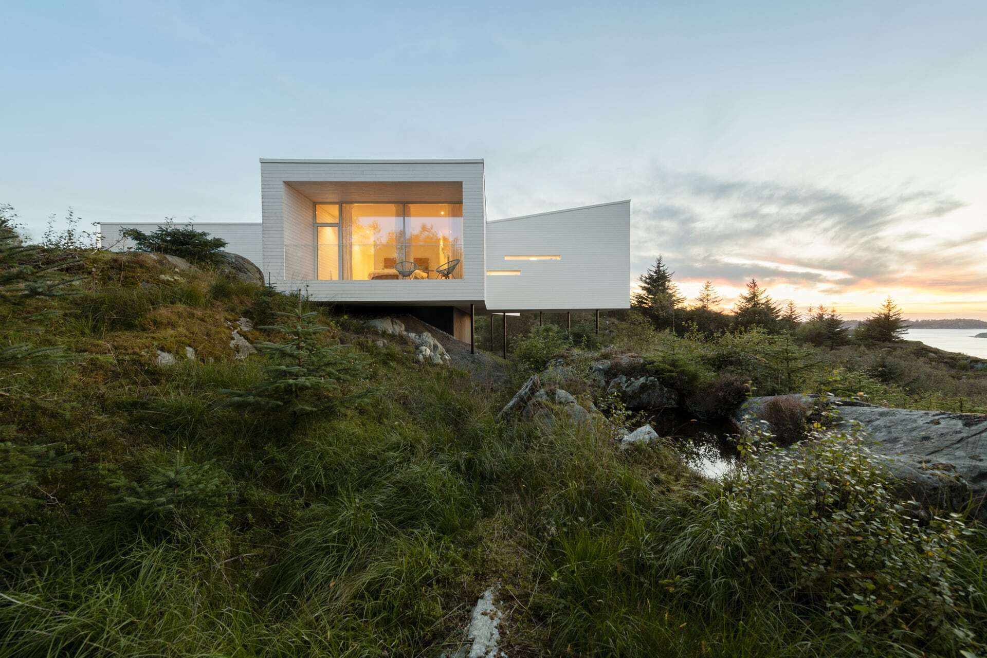 Villa Austevoll plassert i terrenget p&aring; p&aring;ler i ettermiddagslys
